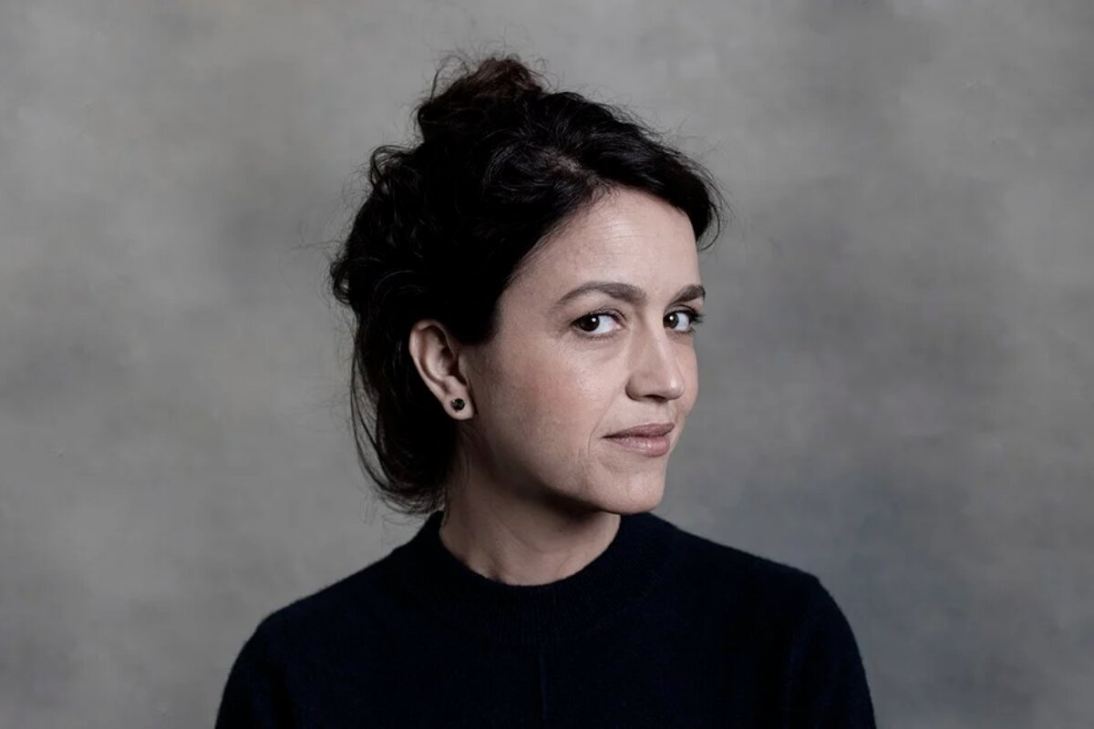 Manuela Dias de perfil, camisa preta, cabelo preso