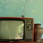 Televisor antigo de tubo com antena sobre uma mesa rústica