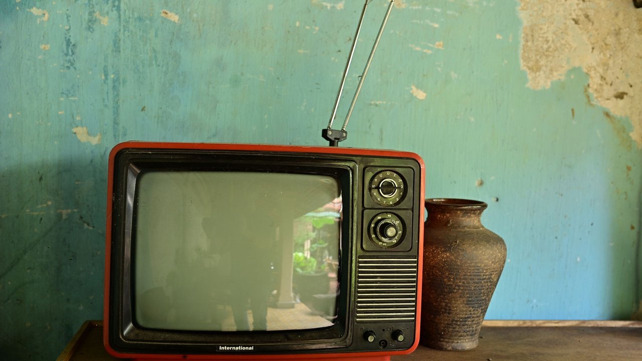Televisor antigo de tubo com antena sobre uma mesa rústica