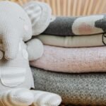 Elefante de pelúcia de tricô ao lado de mantas em tons pastel