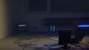 Sala escura com monitores e cabos de equipamento