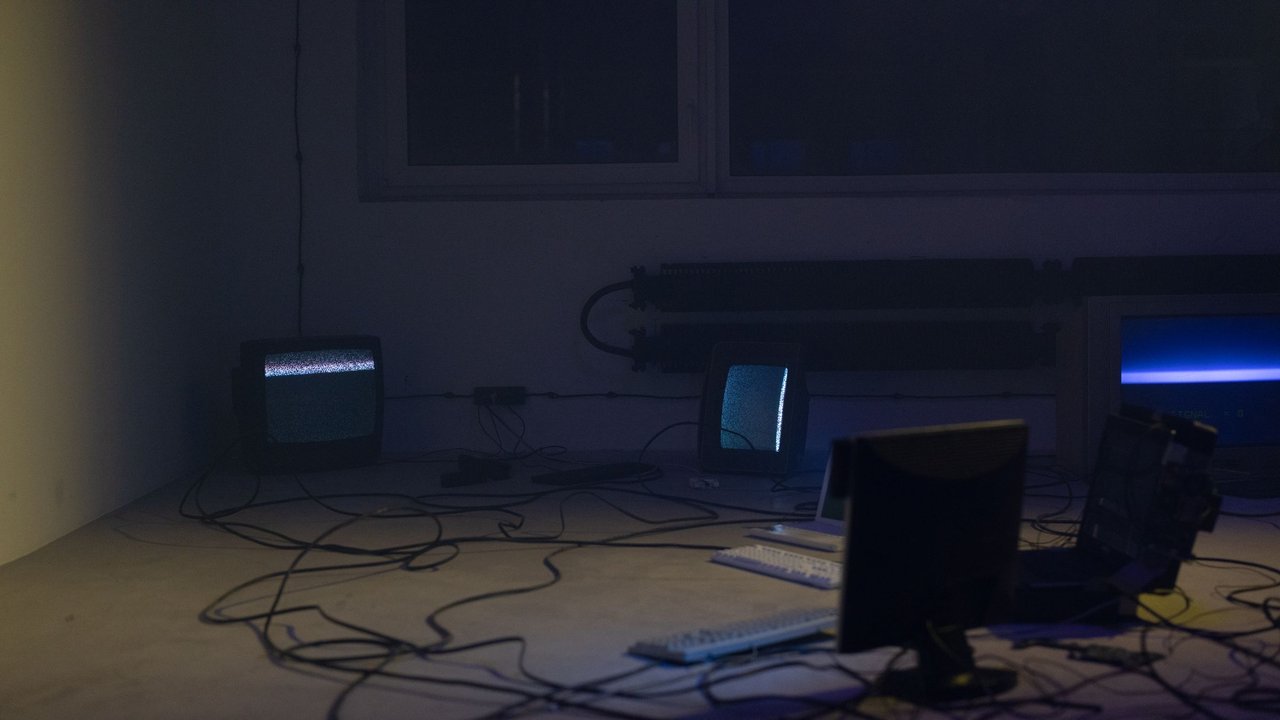 Sala escura com monitores e cabos de equipamento