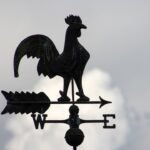 Cata-vento em forma de galo contra o céu nublado