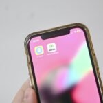 Mão segurando celular com o aplicativo e-Título na tela