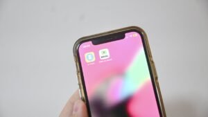 Mão segurando celular com o aplicativo e-Título na tela