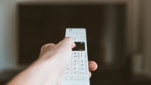 Mão apontando um controle remoto para a televisão