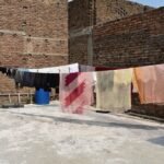 Roupas secando no varal num terraço de tijolos sob o sol