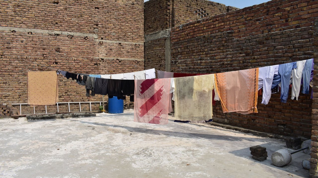 Roupas secando no varal num terraço de tijolos sob o sol