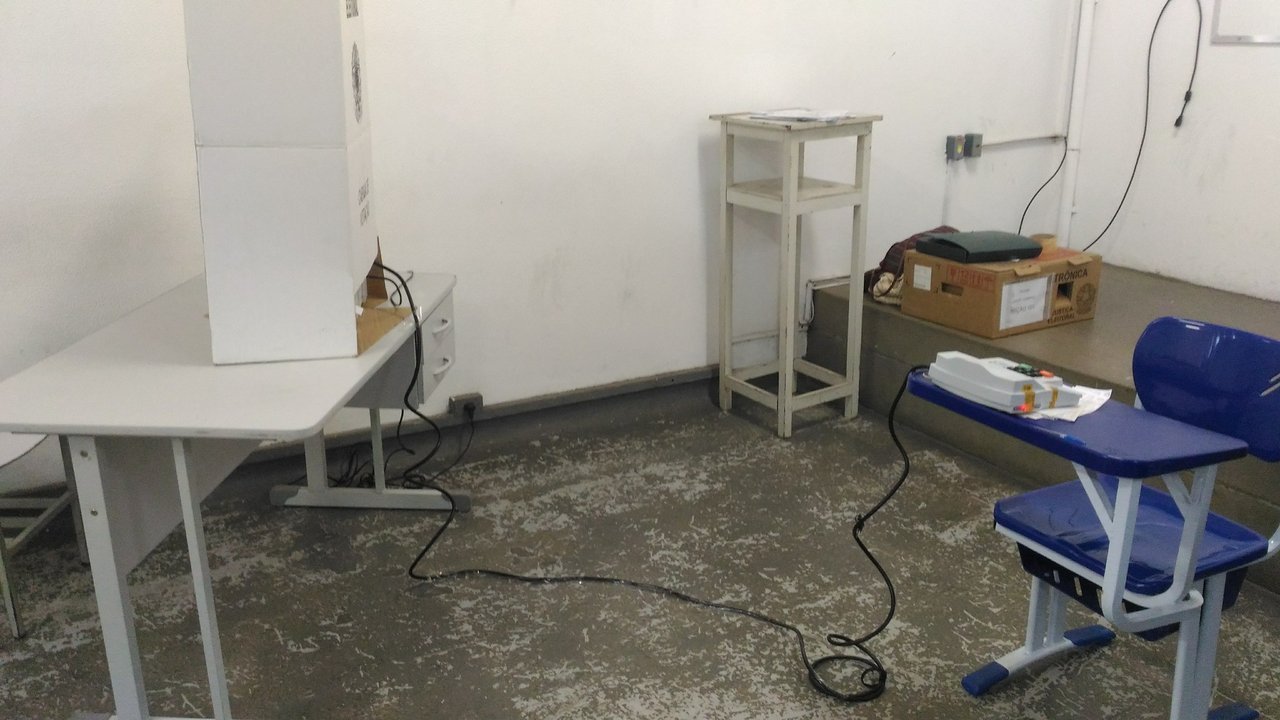 Seção eleitoral vazia com cabine de votação e mesa do mesário