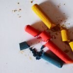 Pedaços de giz colorido quebrados sobre superfície branca
