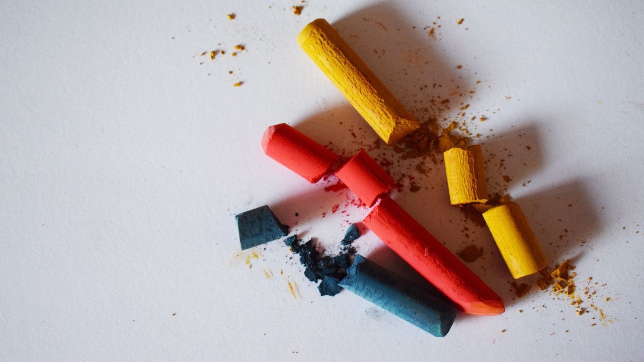 Pedaços de giz colorido quebrados sobre superfície branca