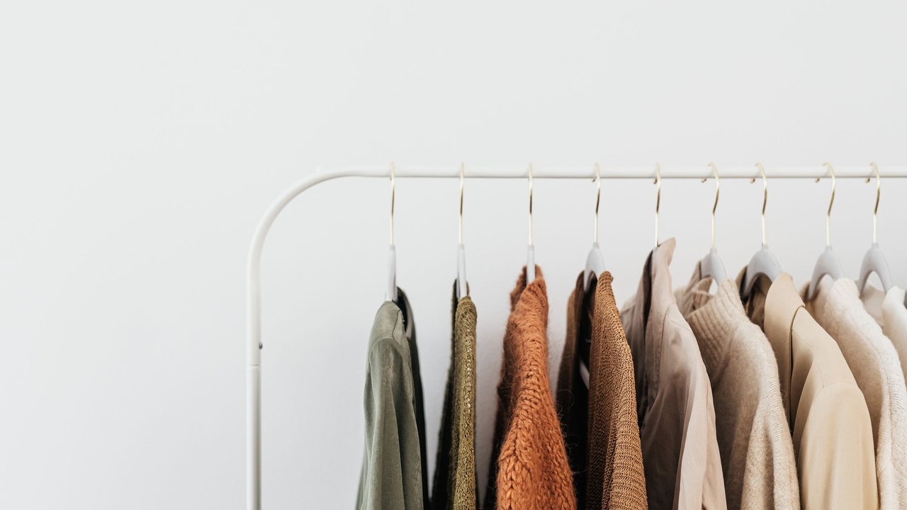 Arara branca com peças de roupa em tons neutros, num fundo claro
