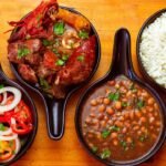 Pratos típicos brasileiros: arroz, feijão, carne e vinagrete em travessas