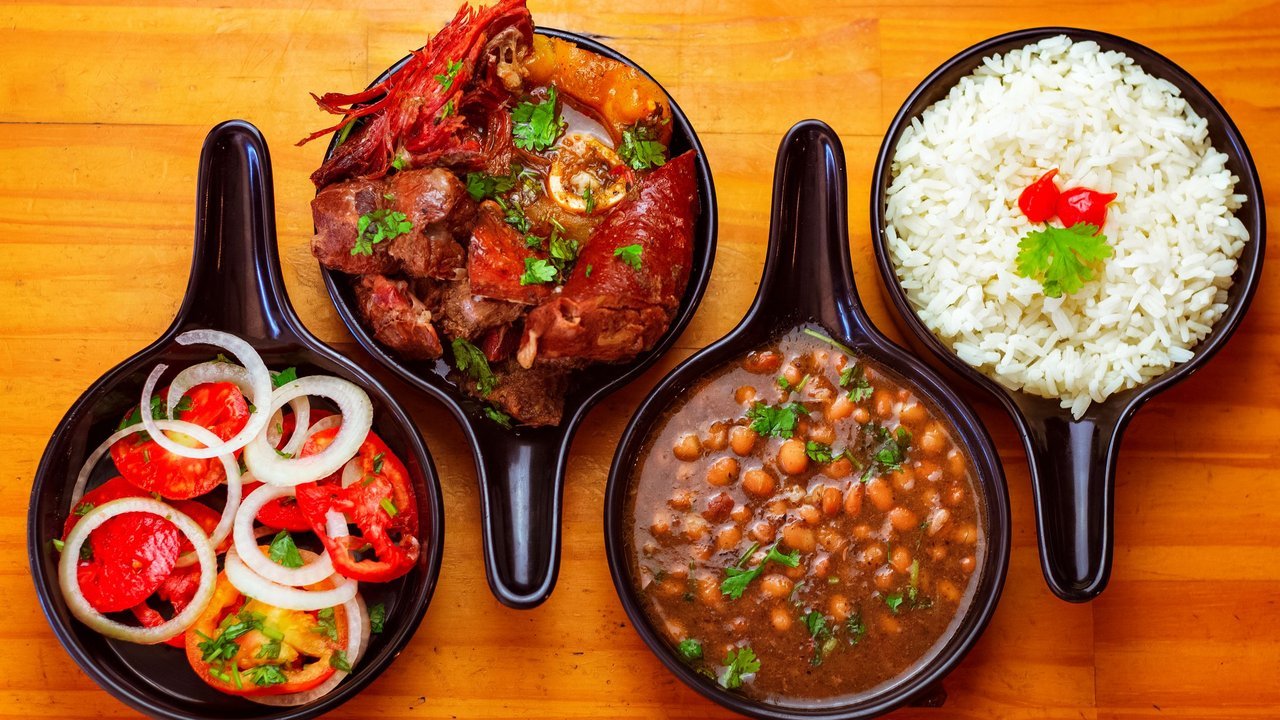 Pratos típicos brasileiros: arroz, feijão, carne e vinagrete em travessas