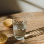 Copo de água e metades de limão sobre uma mesa ao sol