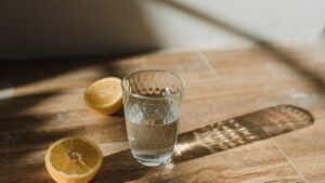 Copo de água e metades de limão sobre uma mesa ao sol