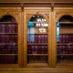 Estante de madeira com livros de capa vermelha numa biblioteca