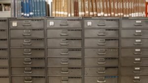 Arquivos de gavetas metálicas sob estantes com livros antigos