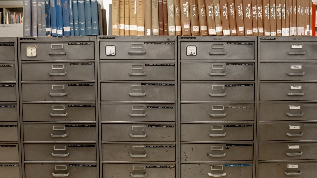 Arquivos de gavetas metálicas sob estantes com livros antigos