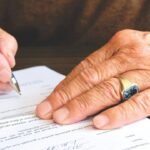Mãos assinando um documento com caneta