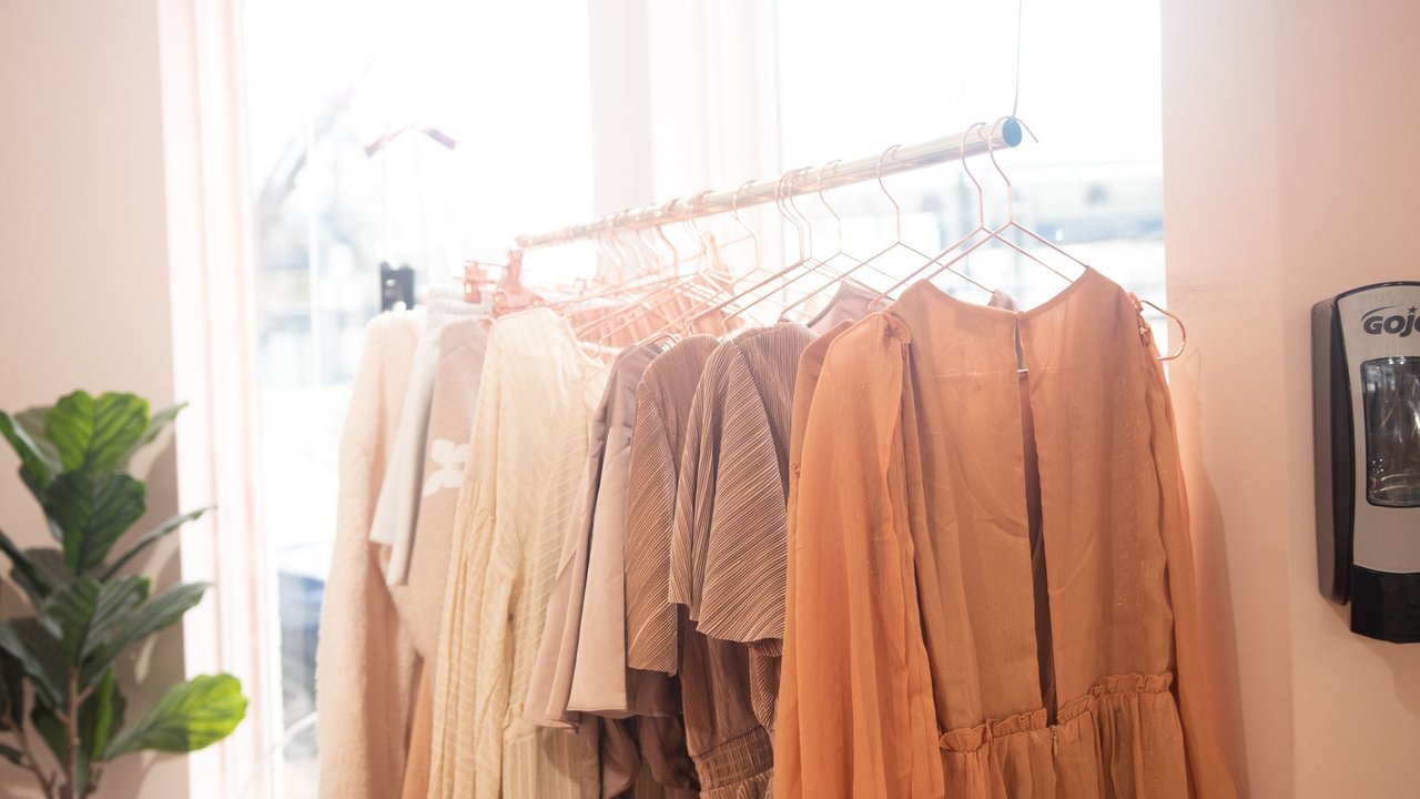 Vestidos em tons terrosos pendurados numa loja iluminada