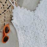 Maiô rendado branco, chapéu de palha e óculos de sol na areia