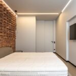 Quarto minimalista com cama e televisor de tela plana na parede
