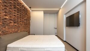 Quarto minimalista com cama e televisor de tela plana na parede