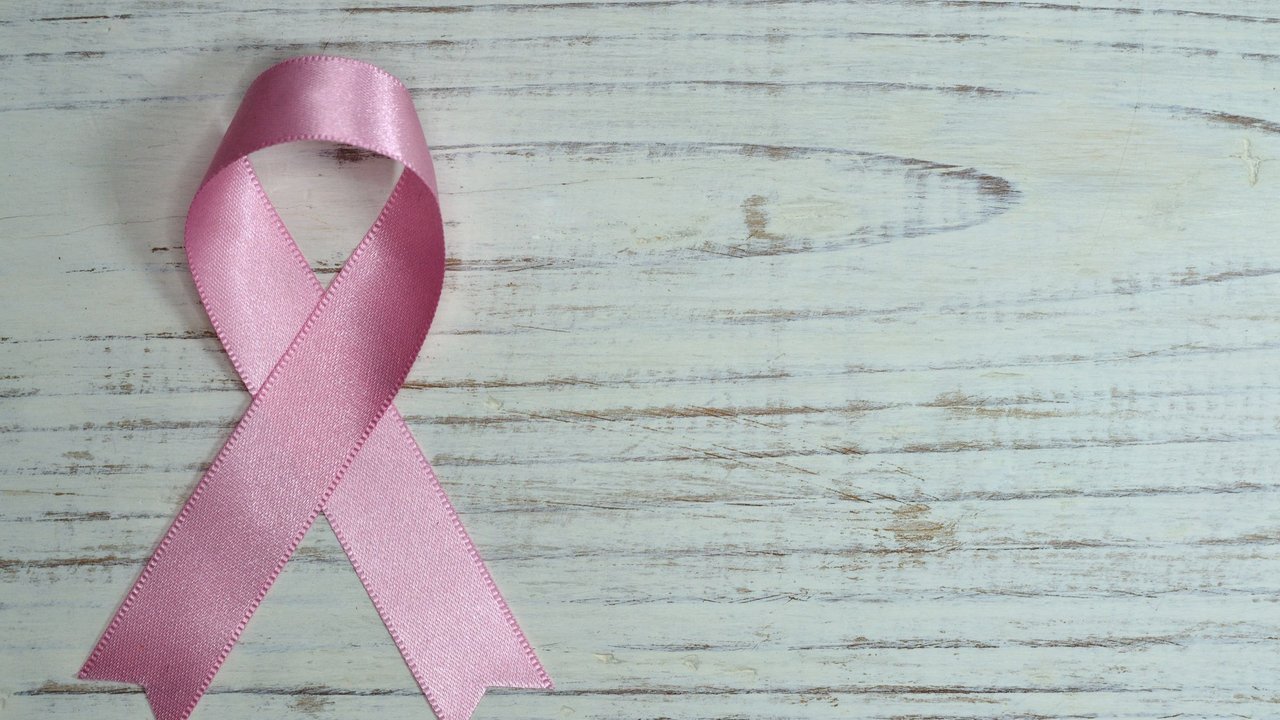 Laço cor-de-rosa da campanha Outubro Rosa sobre fundo de madeira clara