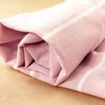 Toalha listrada rosa dobrada sobre fundo bege