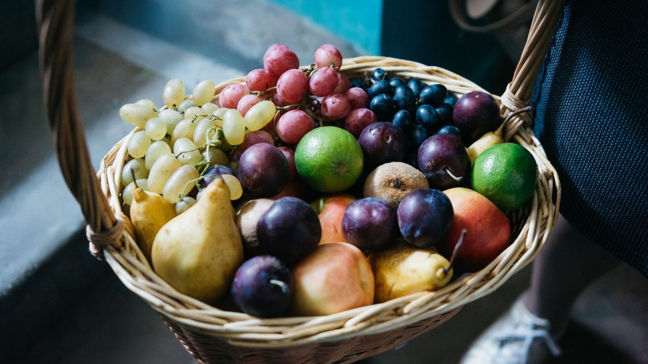 Cesta de vime cheia de frutas: uvas, peras e limas