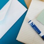 Envelope branco, bloco de notas, post-it e marcador sobre a mesa