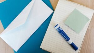 Envelope branco, bloco de notas, post-it e marcador sobre a mesa
