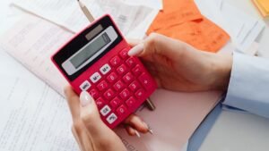 Mãos usando calculadora vermelha sobre recibos e documentos