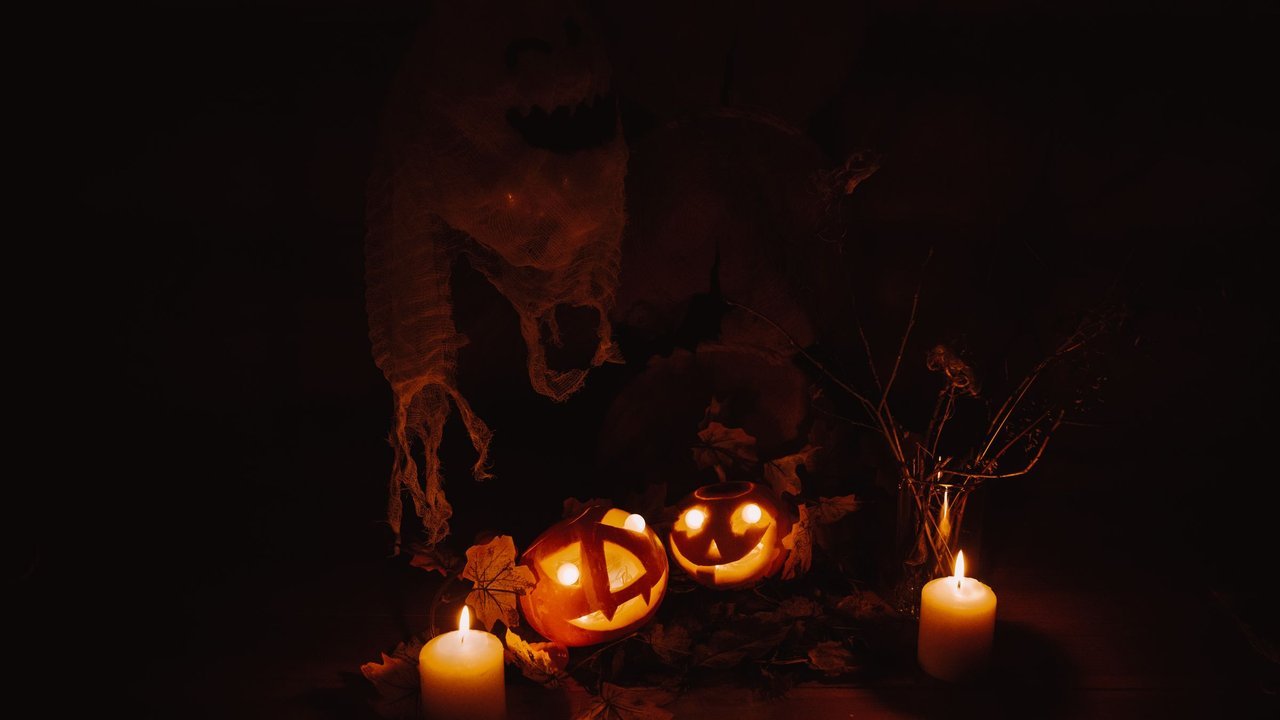 Abóboras esculpidas iluminadas por velas num ambiente escuro