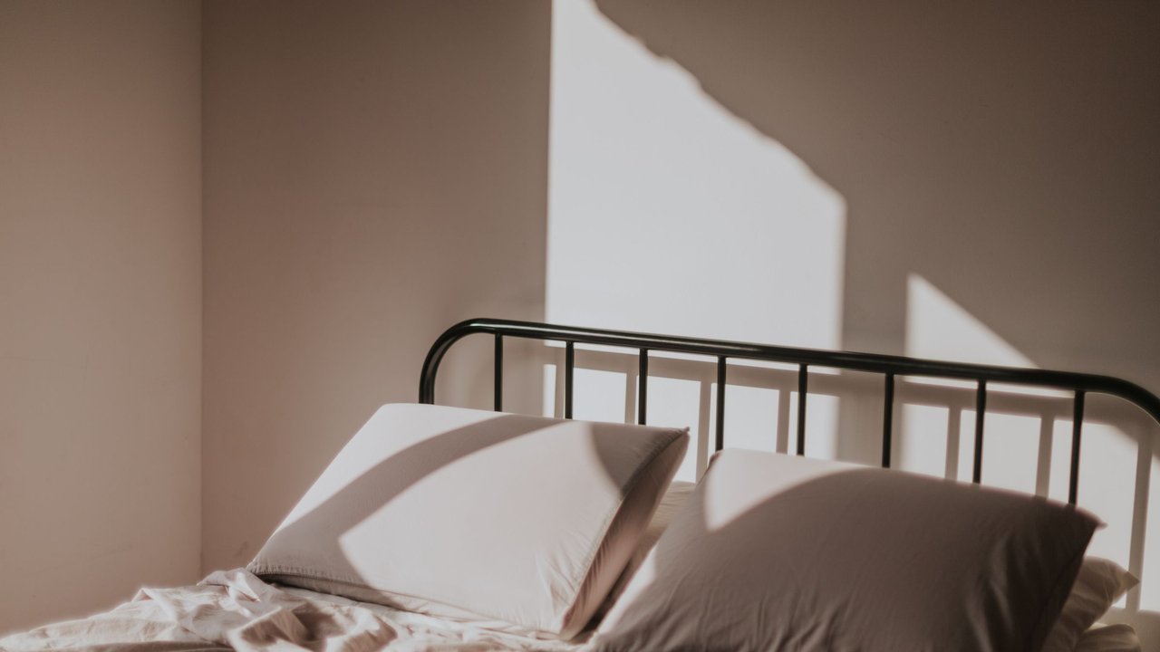 Cama arrumada com travesseiros sob luz suave da manhã