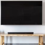Televisor na parede com soundbar sobre um aparador de madeira