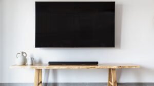 Televisor na parede com soundbar sobre um aparador de madeira