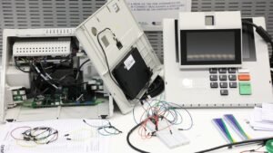 Urna eletrônica aberta com placas e cabos expostos durante teste técnico