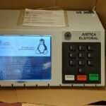 Urna eletrônica da Justiça Eleitoral apoiada sobre uma mesa