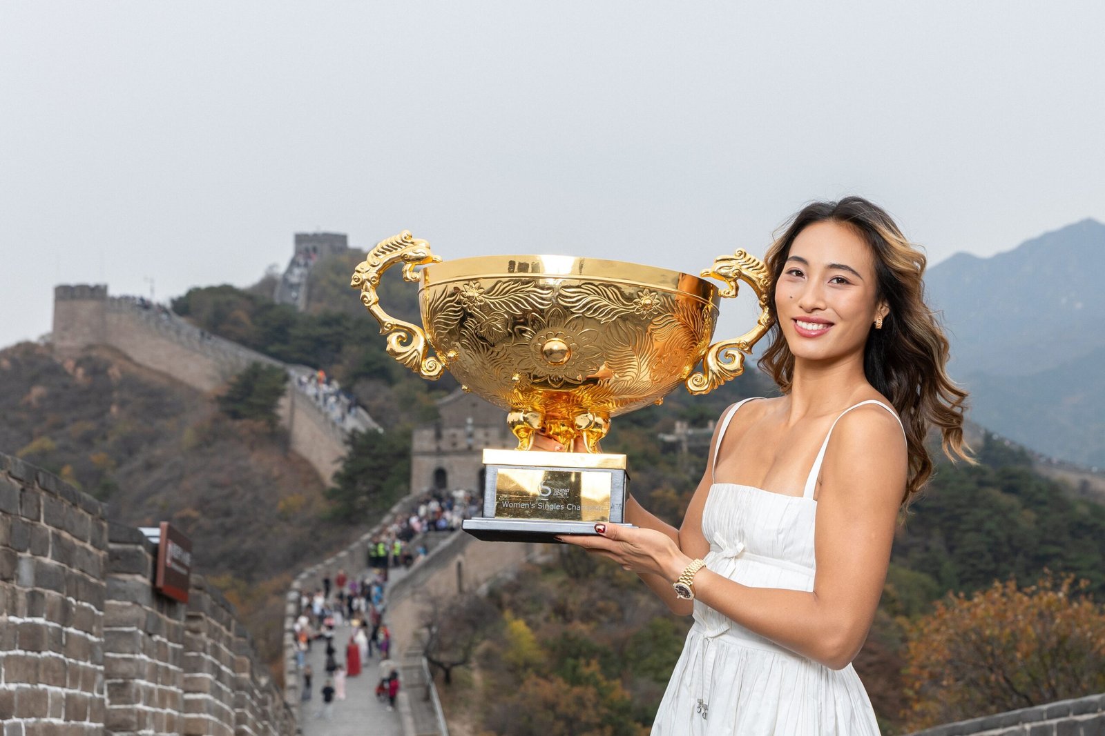 Zheng exibe o troféu do WTA 1000 de Pequim na Muralha da China